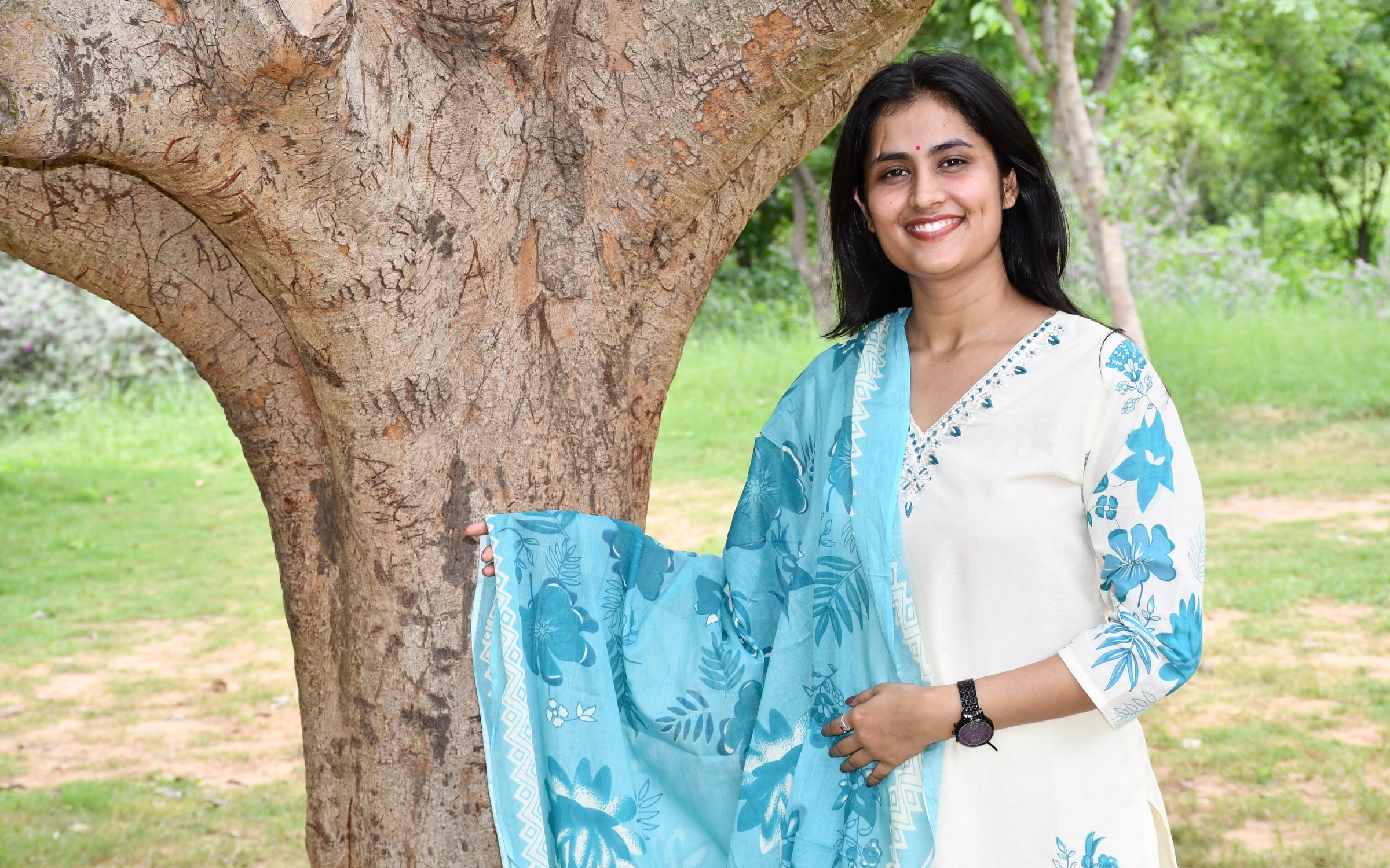 Model wearing the ivory and blue floral suit set beneath a tree
